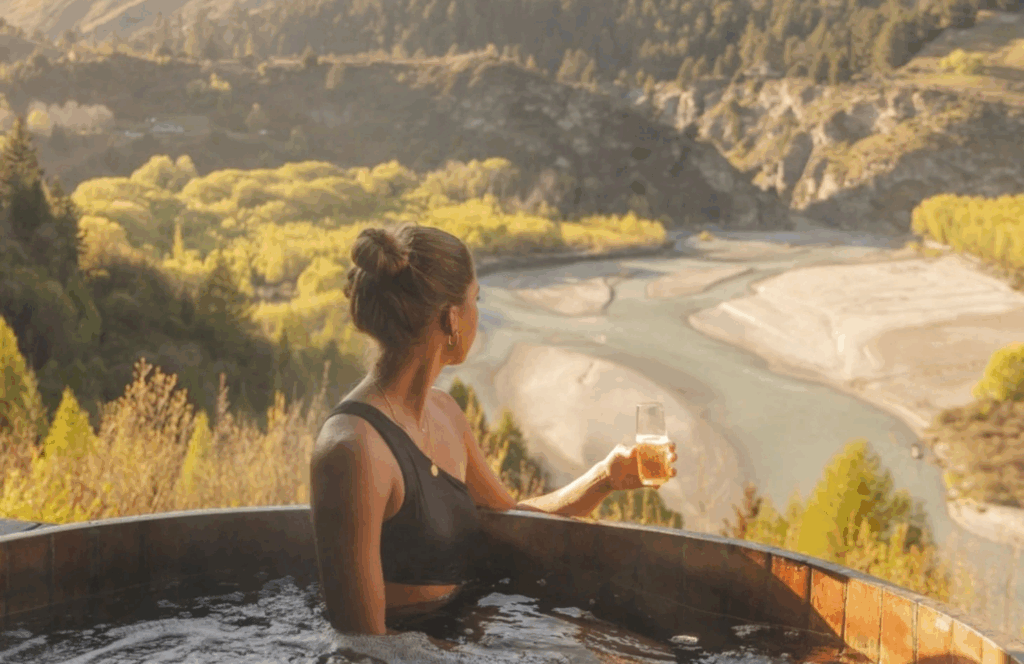 Cedar hot pool overlooking the Shotover River in Queenstown with panoramic alpine views and private bathing experience.